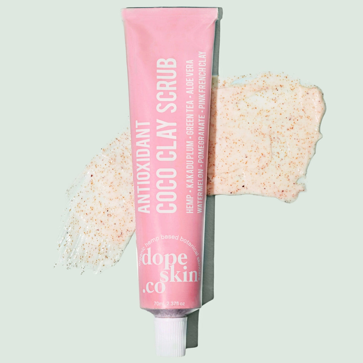 Pink tube of 'Antioxidant Coco Clay Scrub' by dope skin co with scrub residue on a light gray background
