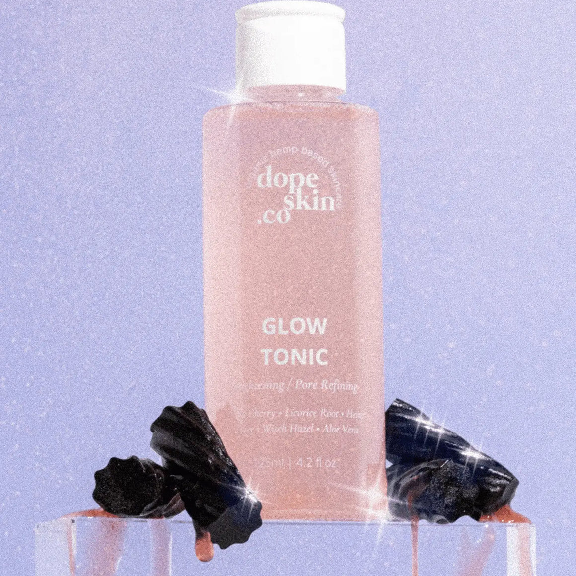 Glow Tonic bottle from Dope Skin Co. with black decorations on a sparkly background for radiant skin.
