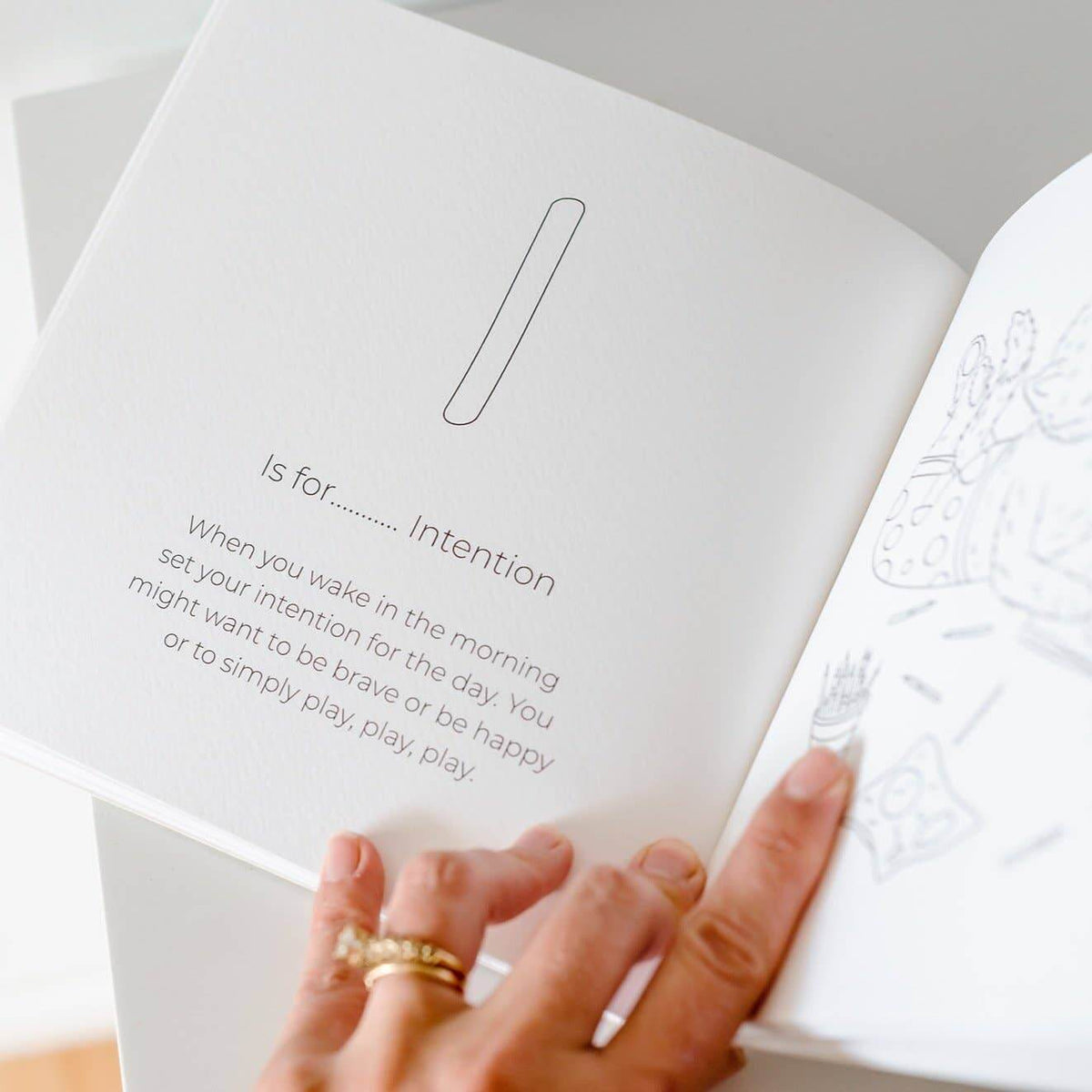 Open book with text and a hand holding it, on a light background