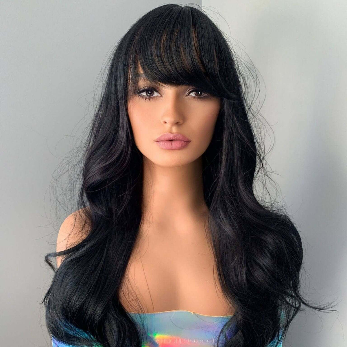 Black wig with bangs on a mannequin head against a plain background