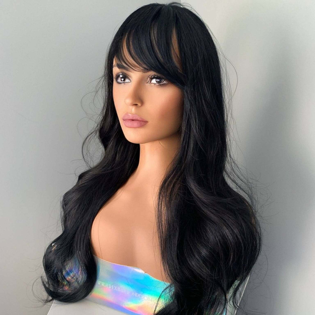 Mannequin head with long black wig on a plain background