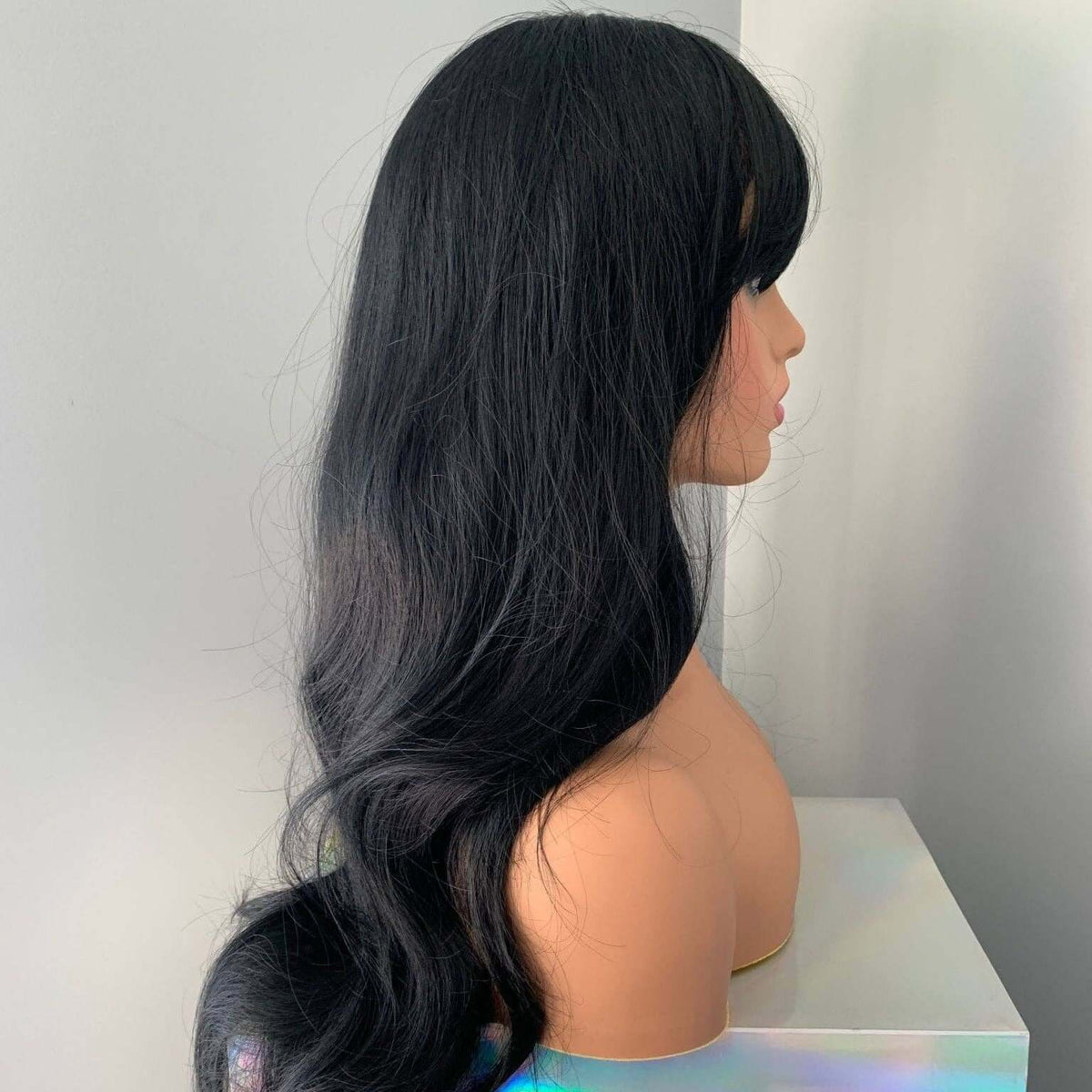 Black wig on a mannequin head with a plain background