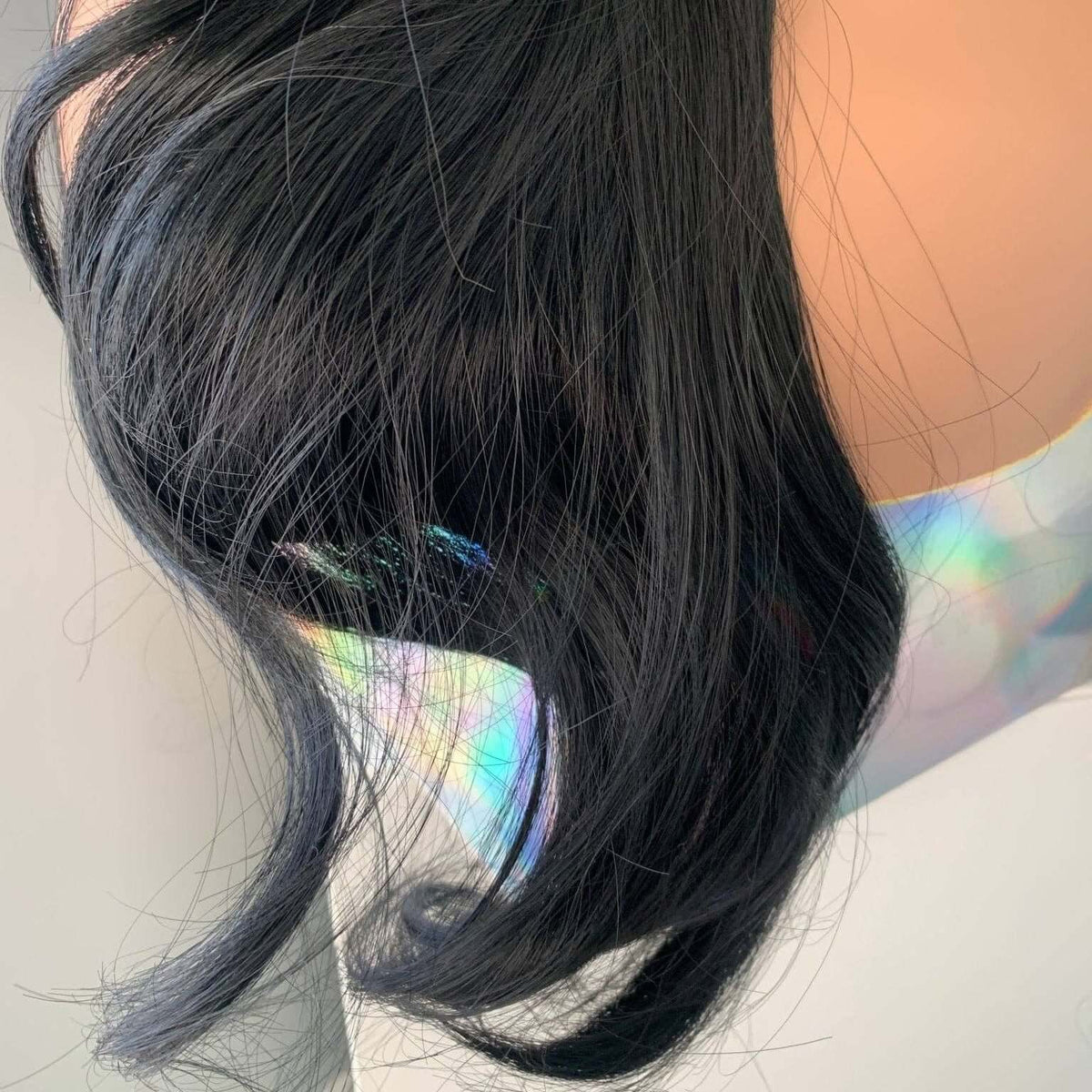 Close-up of a person with long black hair, wearing a white top with colorful patterns.