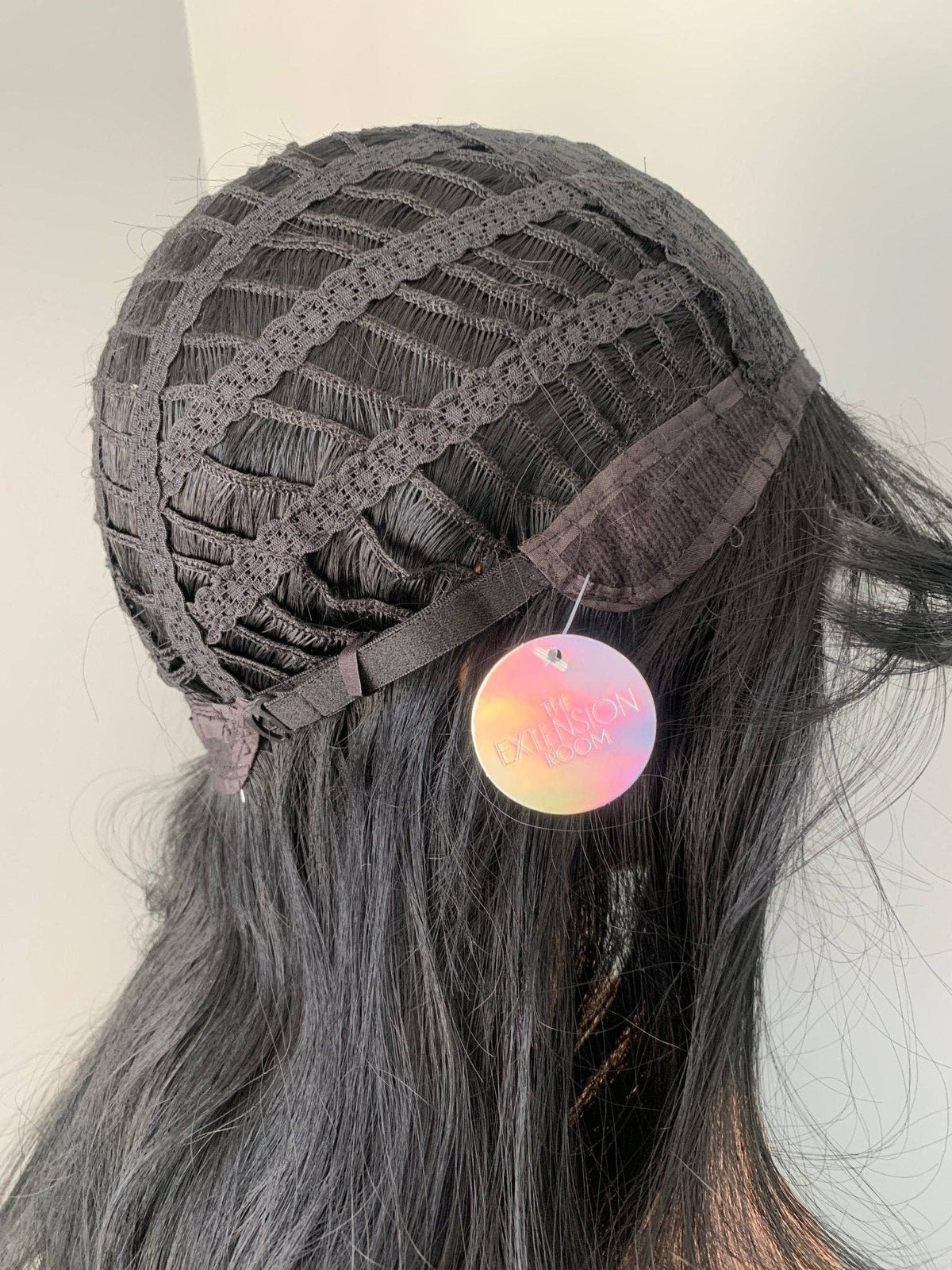 Person wearing a gray lace front wig with colorful earrings on a neutral background