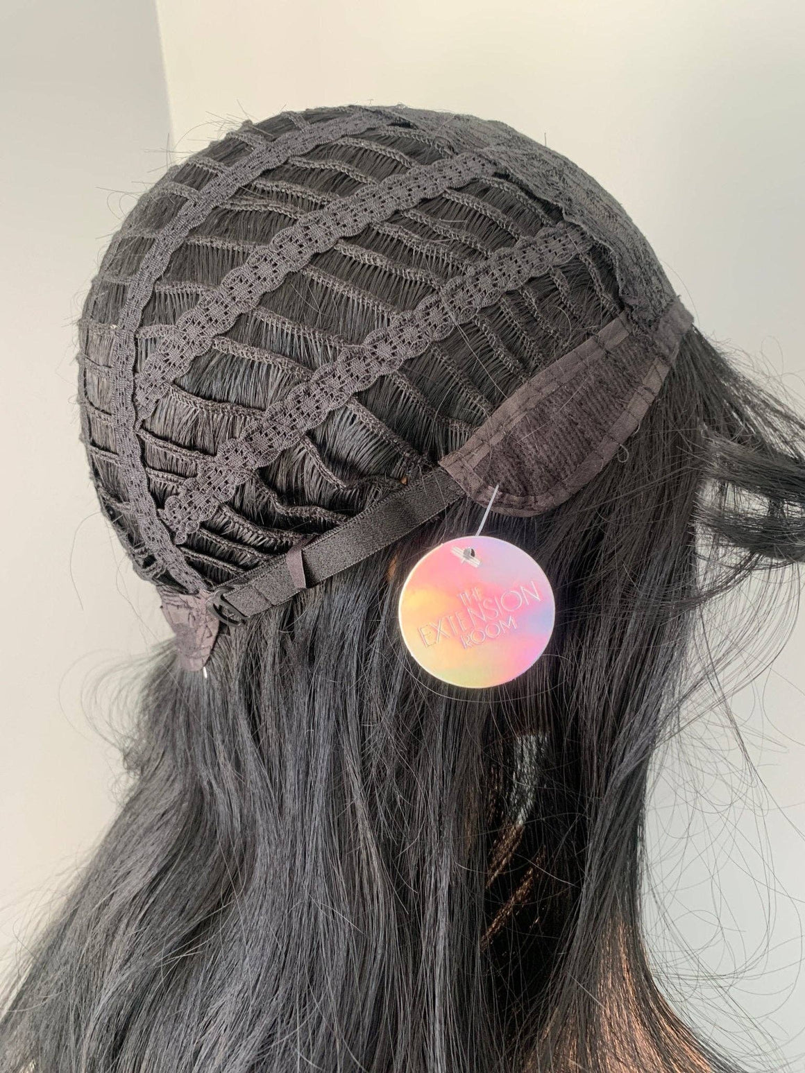 Person wearing a gray lace front wig with colorful earrings on a neutral background