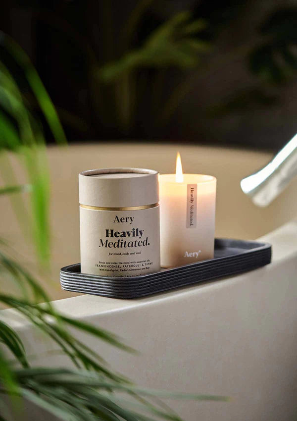 HEAVILY MEDITATED SCENTED CANDLE - FRANKINCENSE PATCHOULI AND THYME - AERY LIVING - LIT CANDLE ON EDGE OF BATH