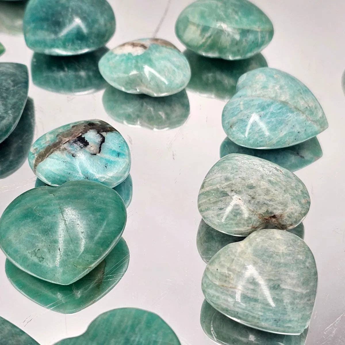 Amazonite Crystal Pocket Hearts, hand carved turquoise stones, showcasing smooth heart shapes on a reflective surface.