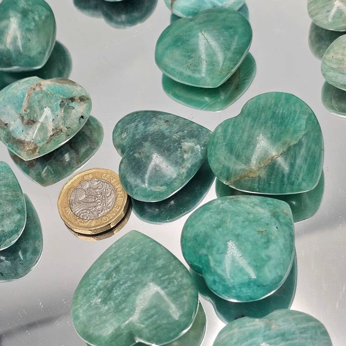 Multiple Amazonite Crystal Pocket Hearts beside a coin, showcasing their calming turquoise hue and smooth finish.
