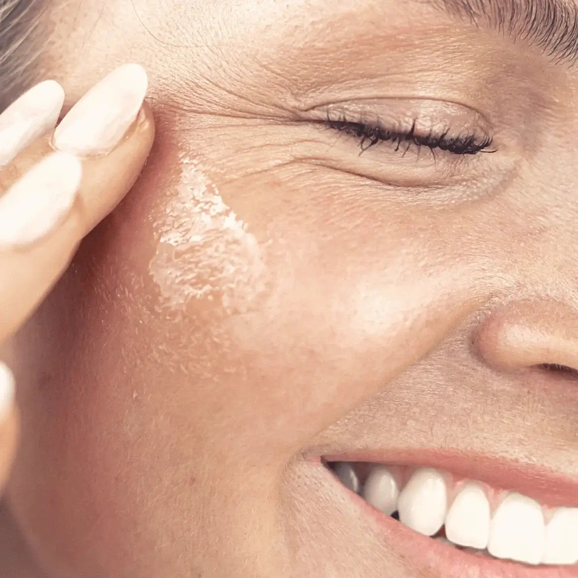 Close-up of a woman applying sunscreen to her face