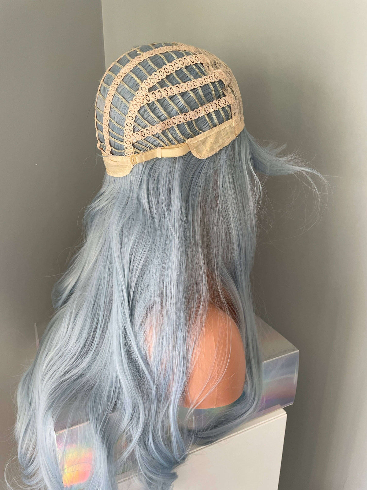 Back view of a light pastel blue wig showcasing its lace cap construction, ideal for styling and comfort. Blue Wig.