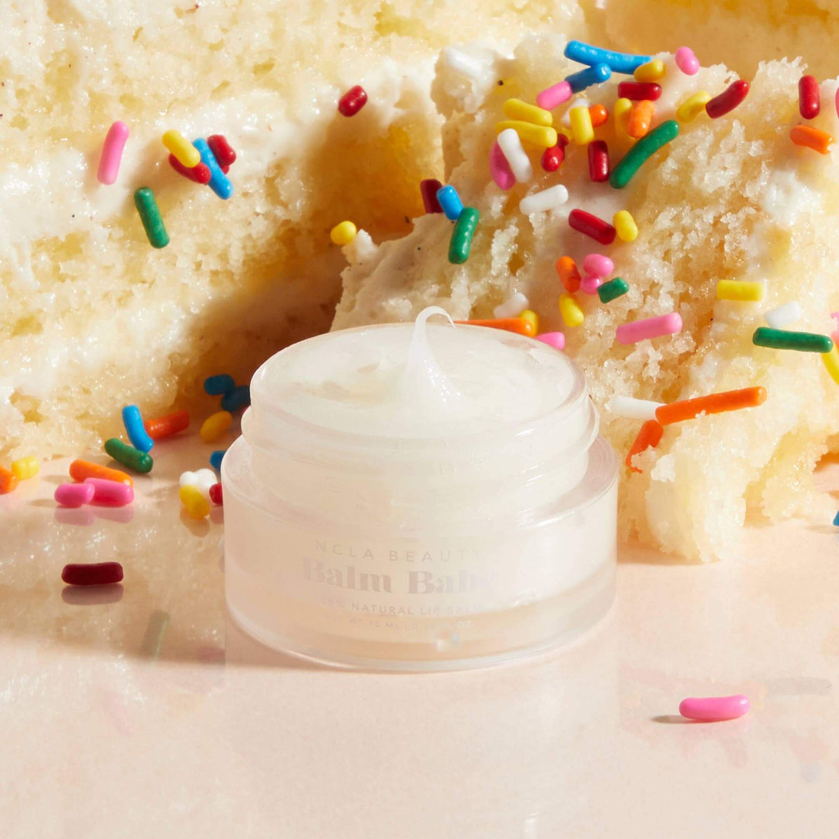 Balm Bar lip balm on a cake with colorful sprinkles