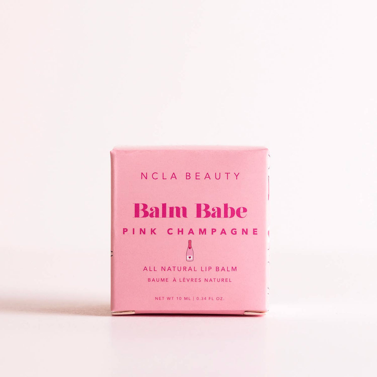 Pink lip balm packaging with 'NCLA Beauty' branding on a light pink background