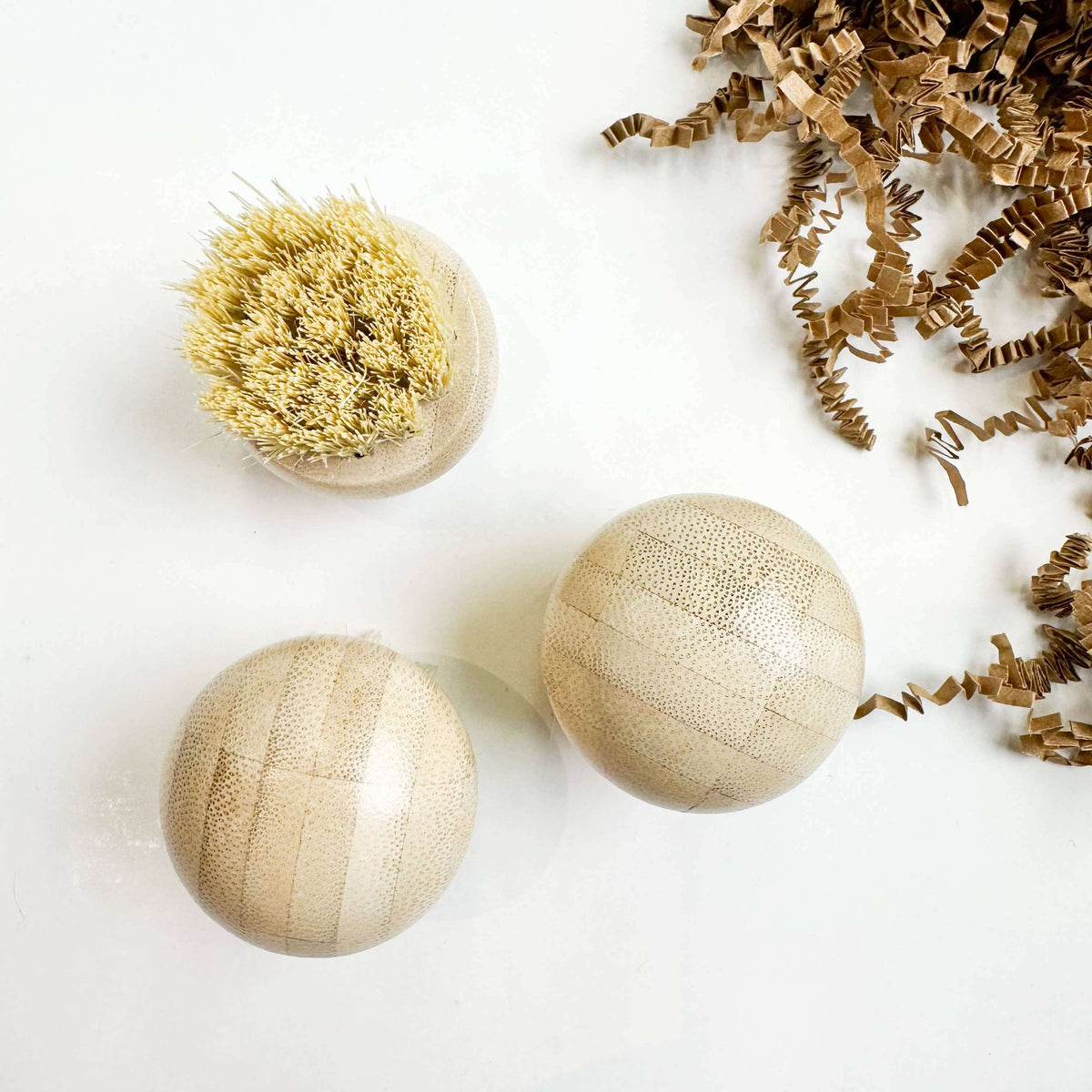 Three wooden bath bombs with a natural bristle brush on a white background