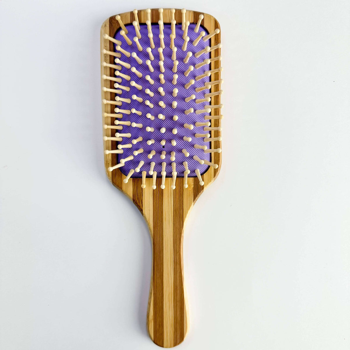 Bamboo Paddle Hair brush - Smile Boutiques with smooth bristles on a purple cushion for gentle hair care.