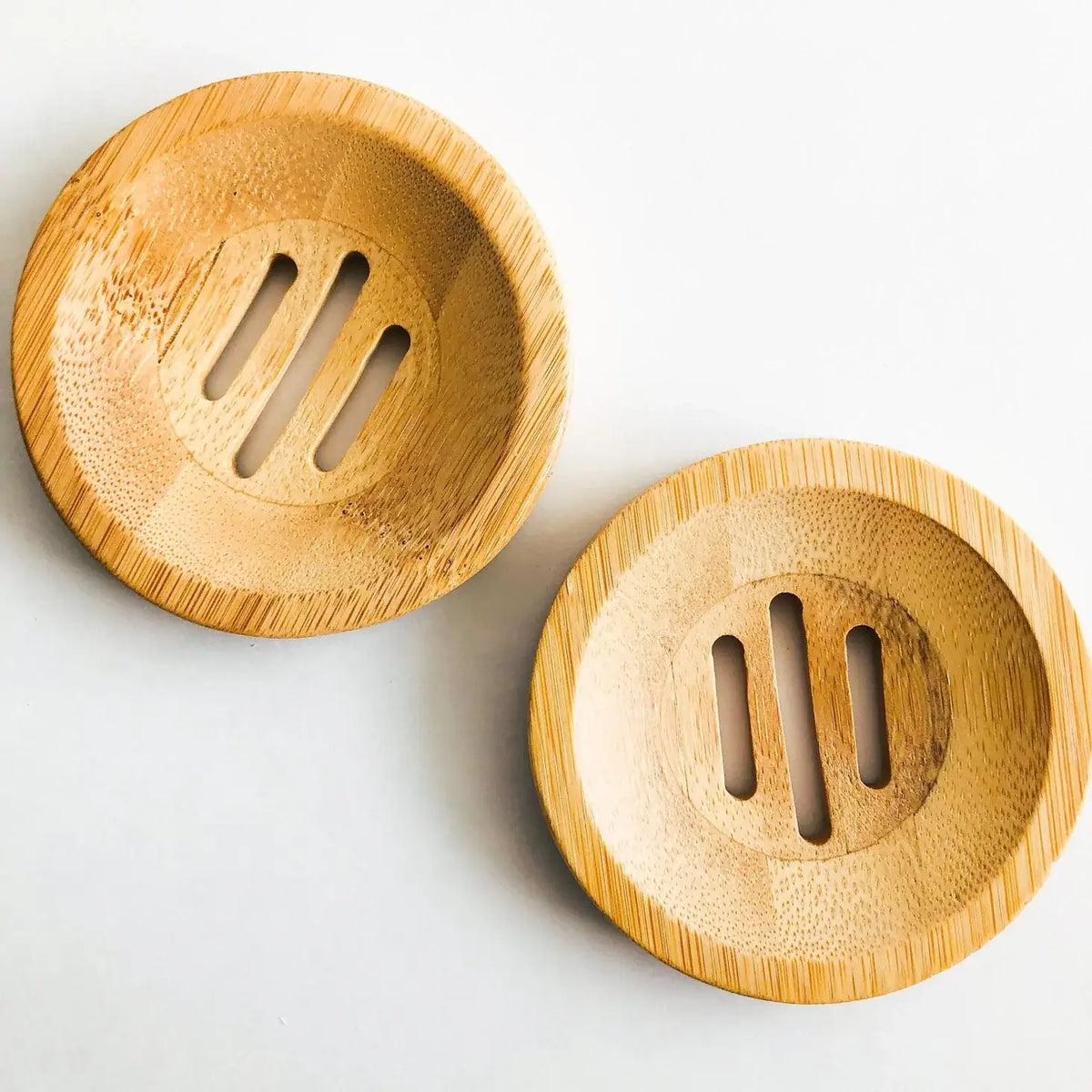 Two wooden coasters with slotted design on a light gray background