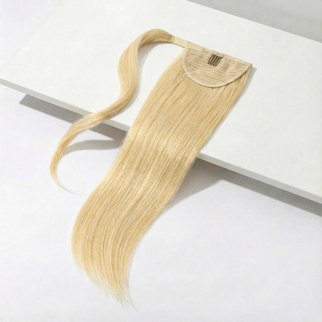 Beach blonde ponytail hair extension lying on a white surface, showcasing its silky straight texture and clip-in design.