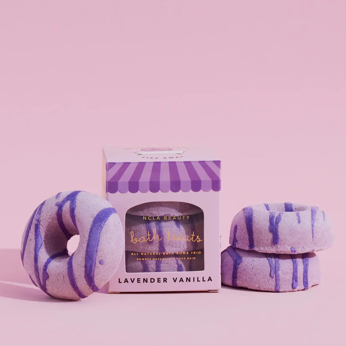 Bath bombs with purple stripes and a box labeled 'NCLA Beauty' on a pink background