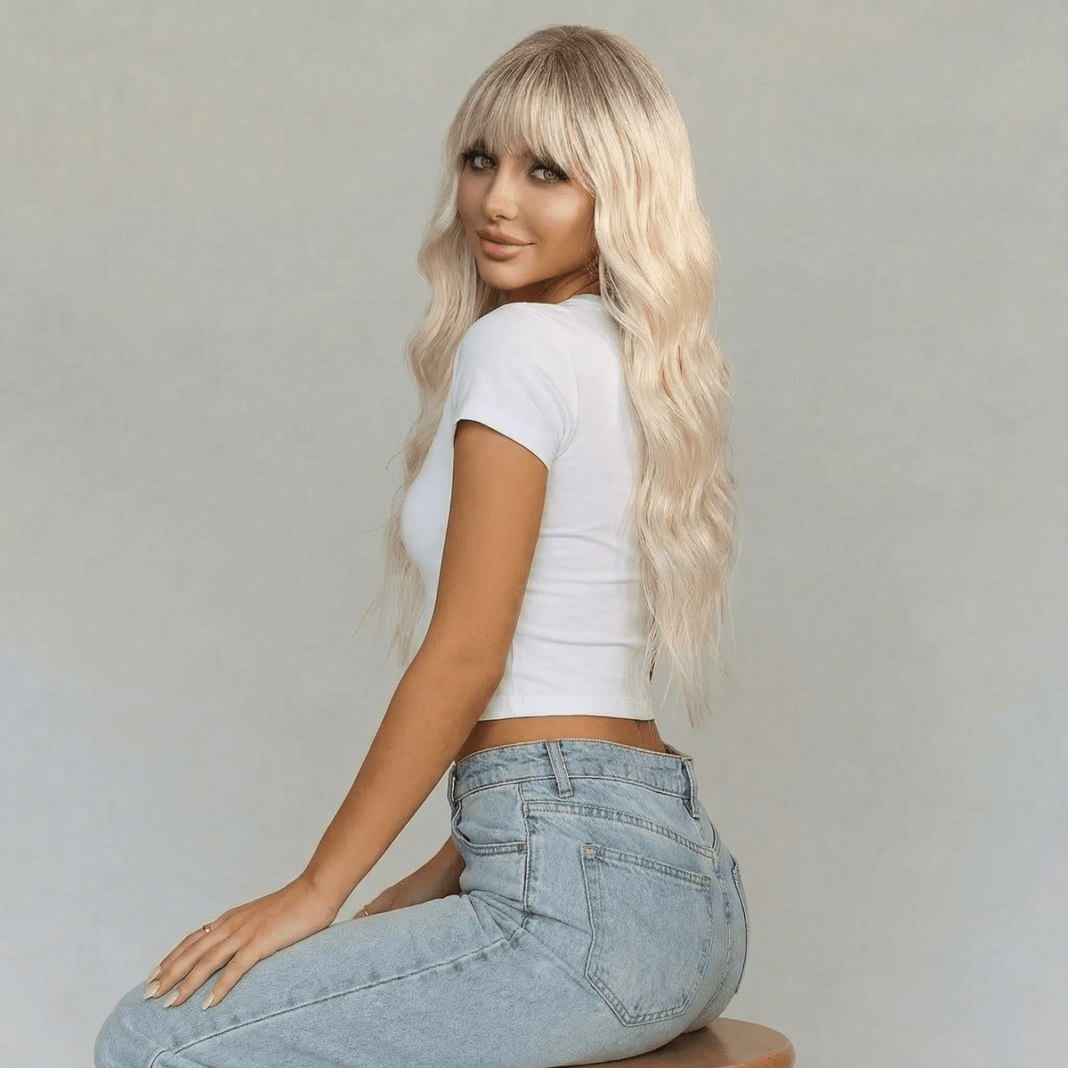 Blaire Ash Blonde Beach Wave Synthetic Wig with Bangs styled on a model with long, tousled waves.
