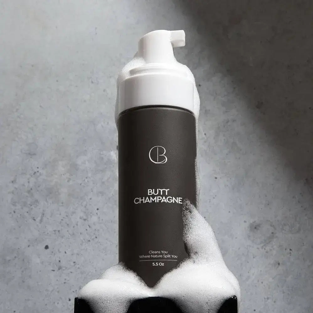 Bottle of 'Butt Champagne' with a foamy texture against a gray background