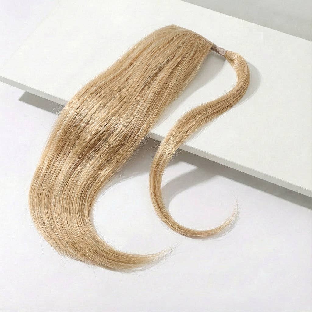 Buttery blonde ponytail hair extension displayed on a sleek surface, showcasing its silky straight texture and length.