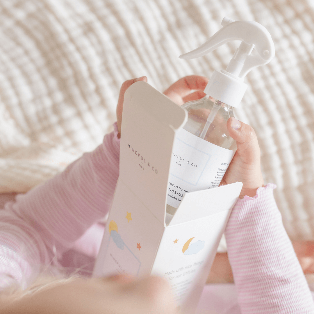 Person holding a clear spray bottle with a white label against a blurred background