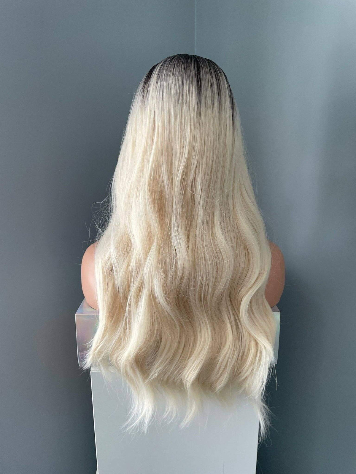 Blonde wig on a mannequin head against a plain background