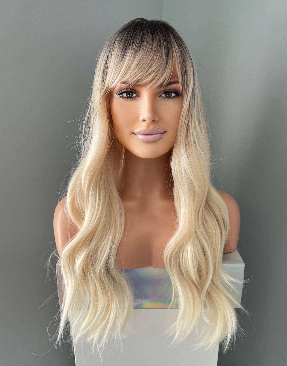 Mannequin head with long blonde wig on a gray background