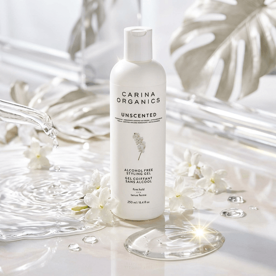 Carina Organics unscented styling gel bottle on a decorative background with flowers and water.