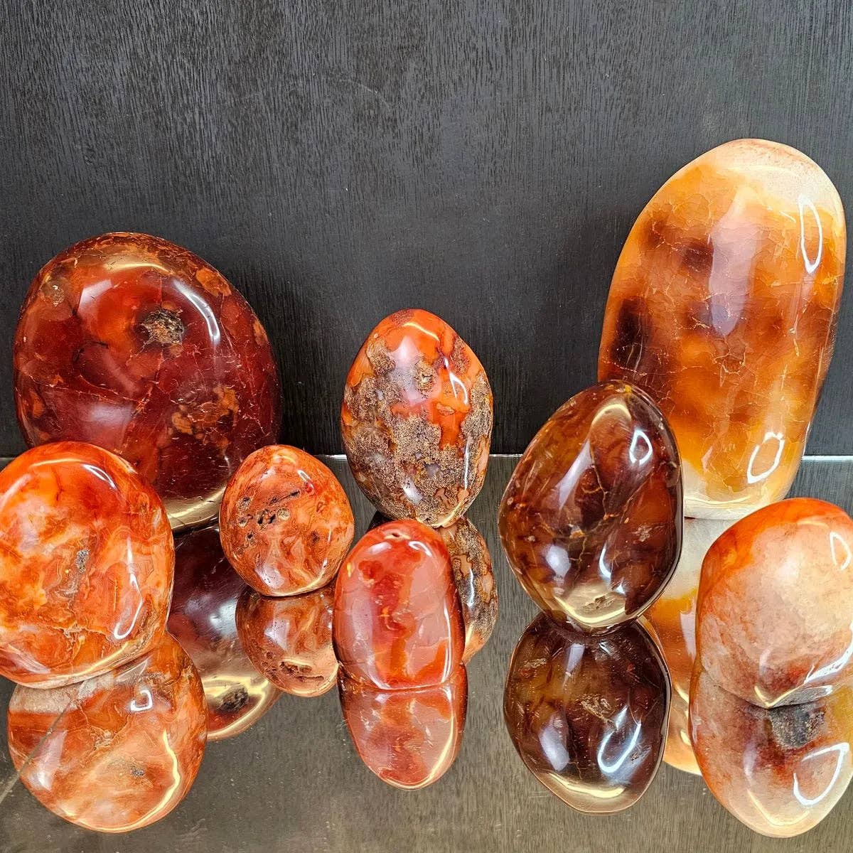 Collection of polished amber stones on a reflective surface with a dark background