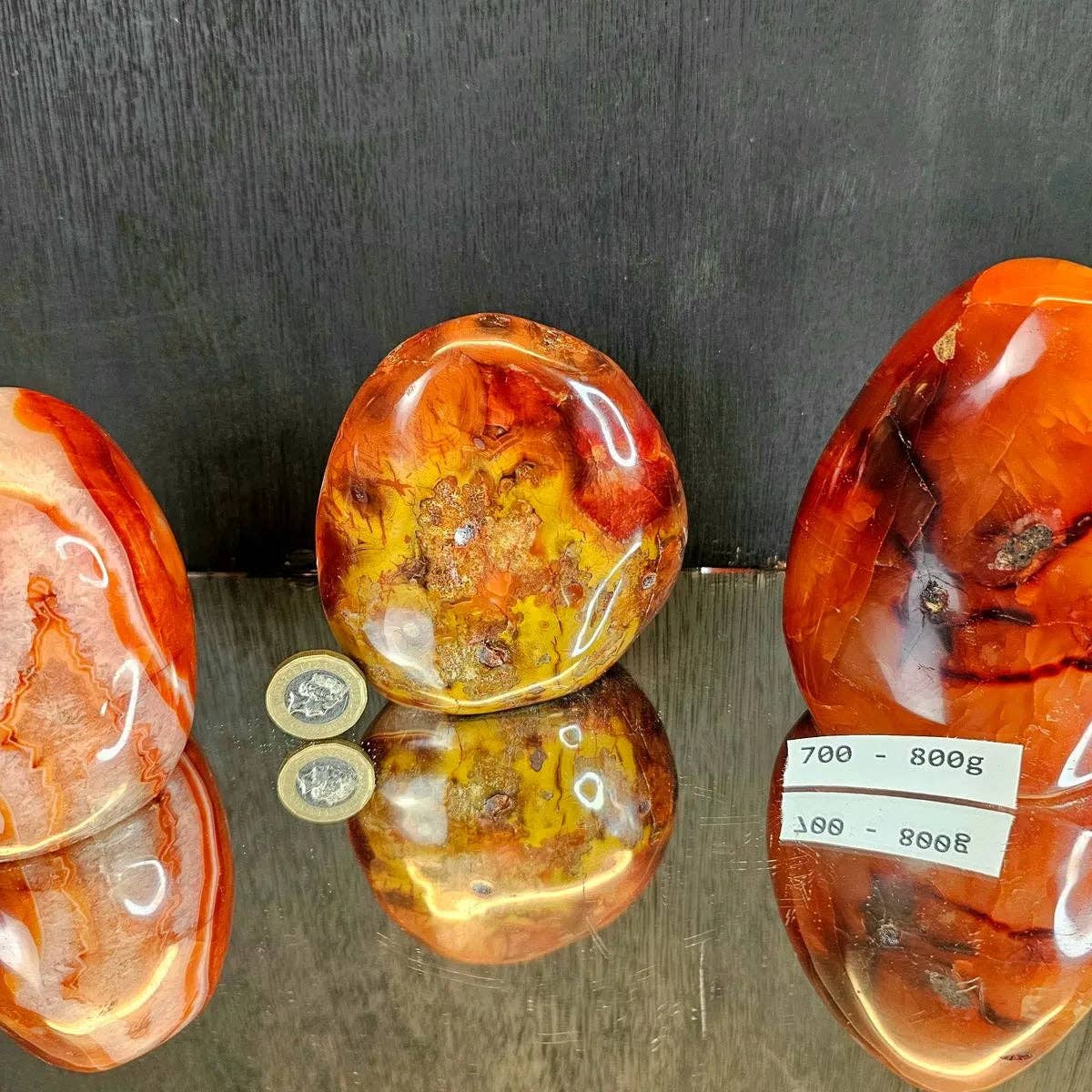 Three polished amber stones on a reflective surface with a dark background