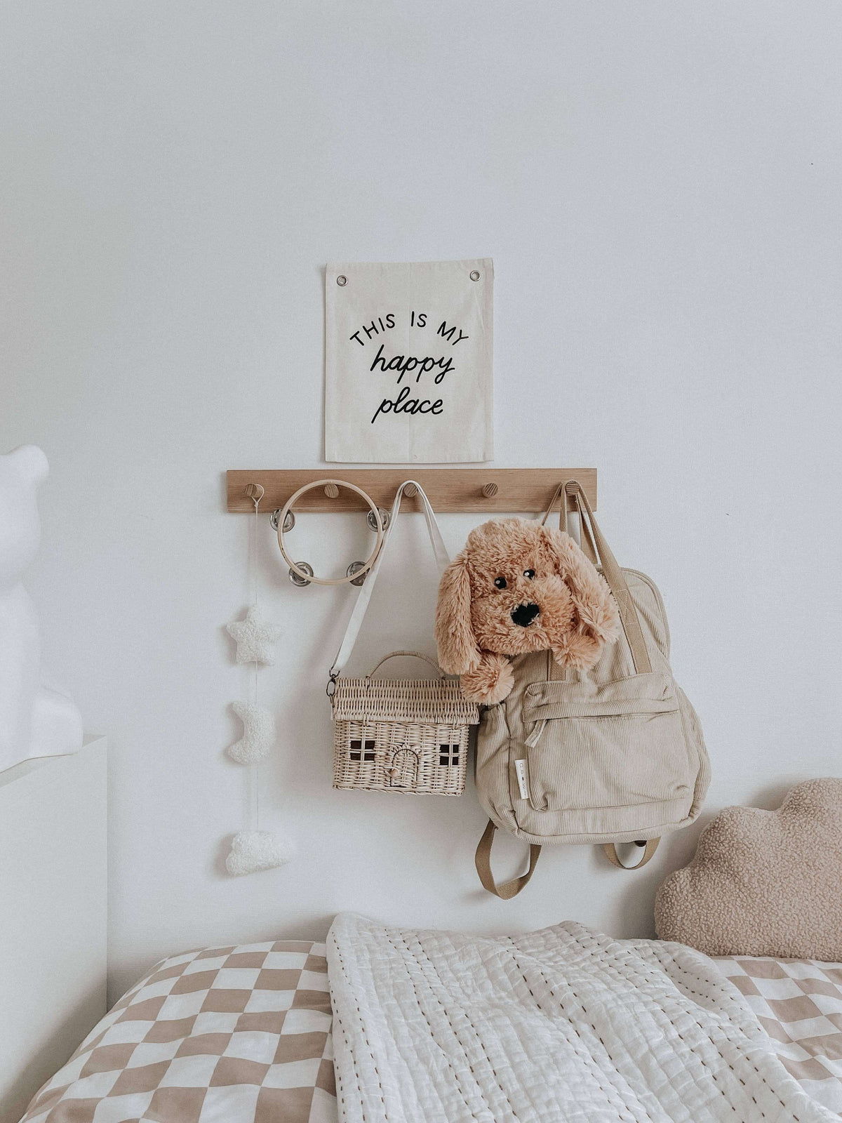 Charlie The Weighted Puppy Dog Teddy hanging on a wooden rack with a backpack and decor in a cozy room.