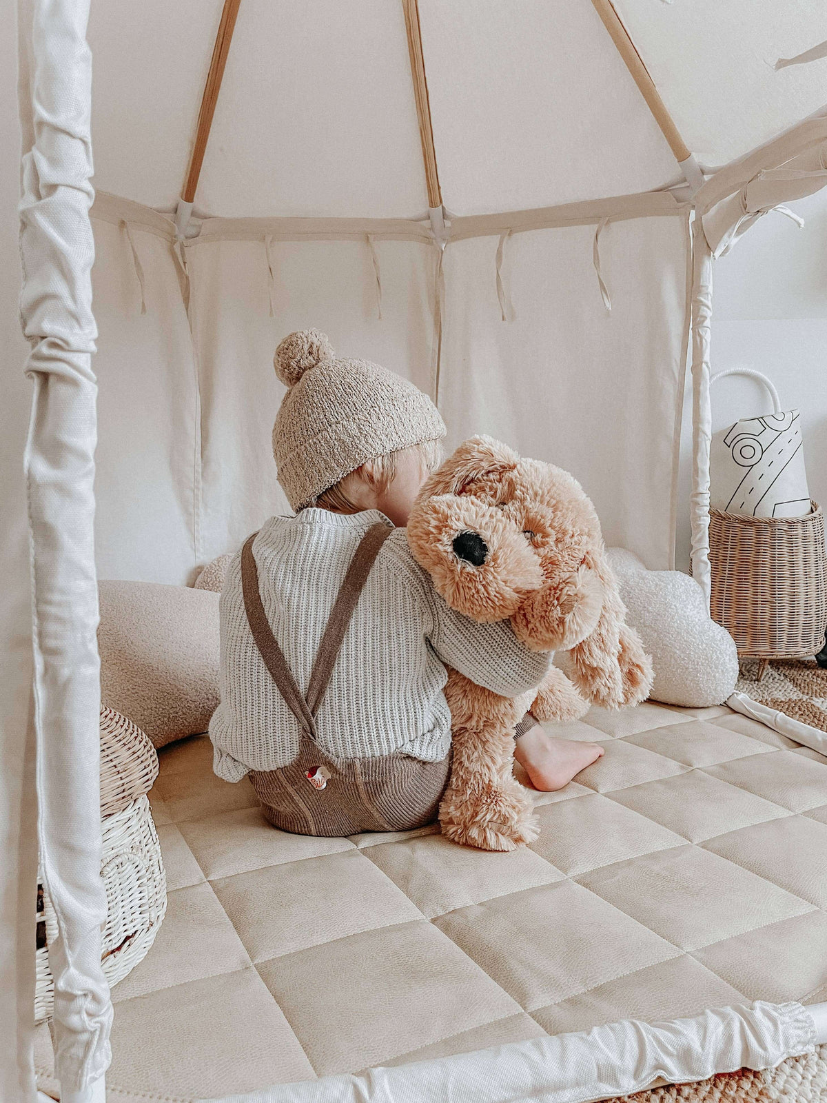 Child sitting beside Charlie The Weighted Puppy Dog Teddy in a cozy tent setting.