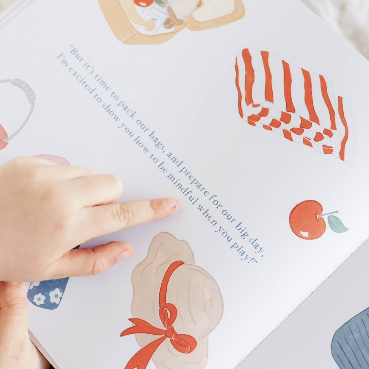 Child's hand pointing to a page in Charlie's Mindful Adventures By The Sea, featuring colorful illustrations and a mindfulness message.