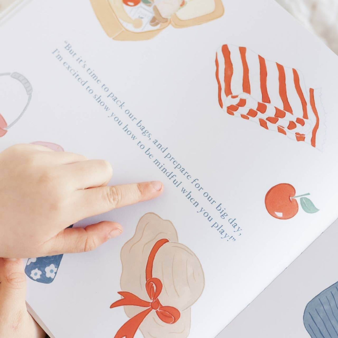 Child's hand pointing to a page in Charlie's Mindful Adventures By The Sea, featuring colorful illustrations and a mindfulness message.