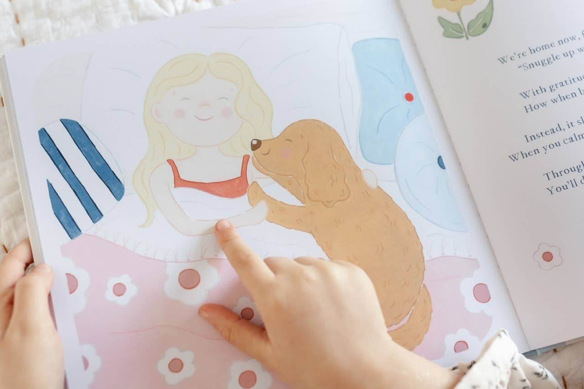 A child pointing to an illustration from Charlie's Mindful Adventures By The Sea featuring a girl and a puppy.