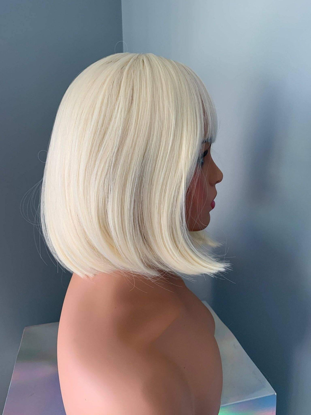 Mannequin head with a blonde bob wig against a neutral background
