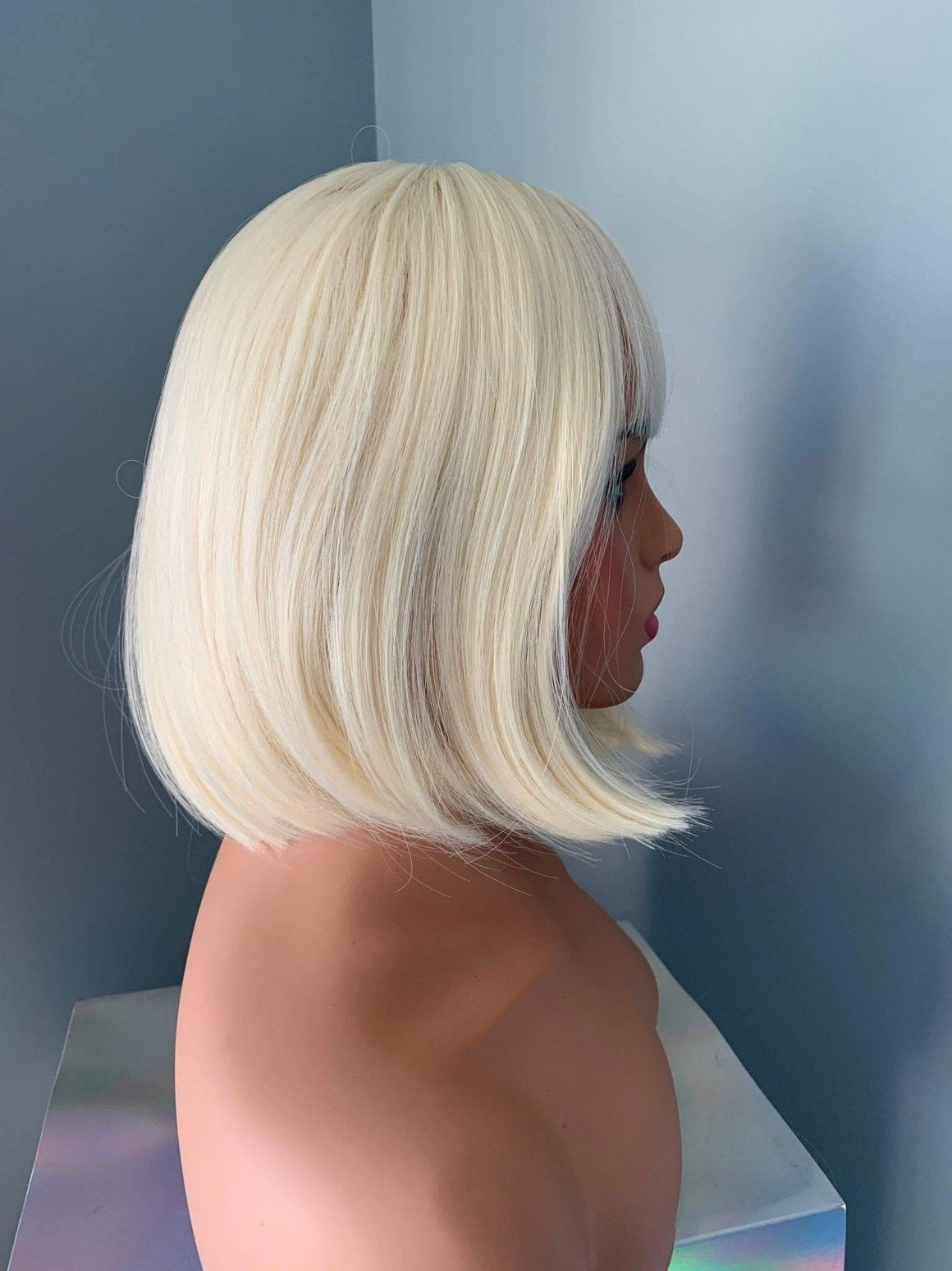 Mannequin head with a blonde bob wig against a neutral background