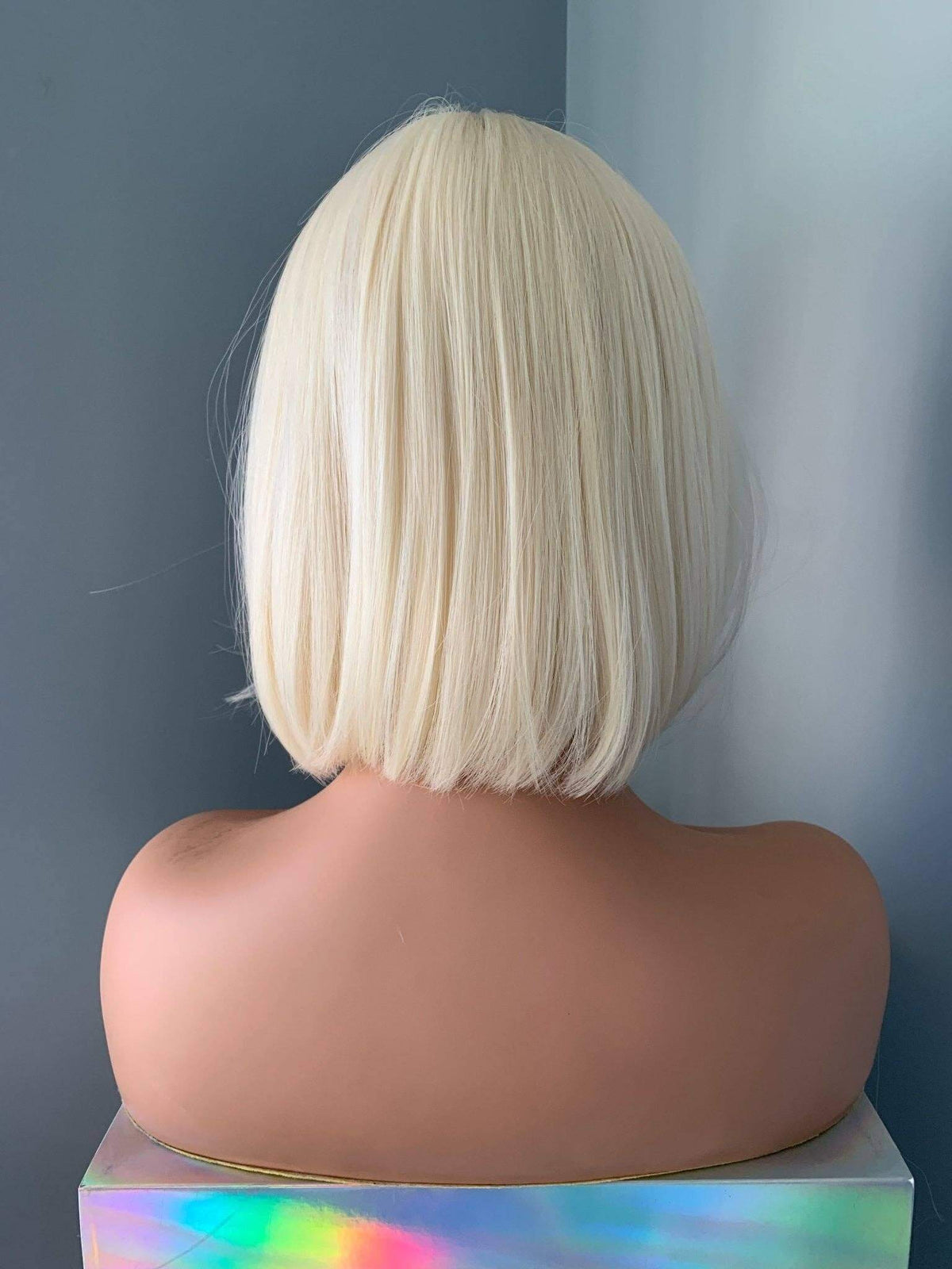 Mannequin head with a blonde bob wig against a gray background