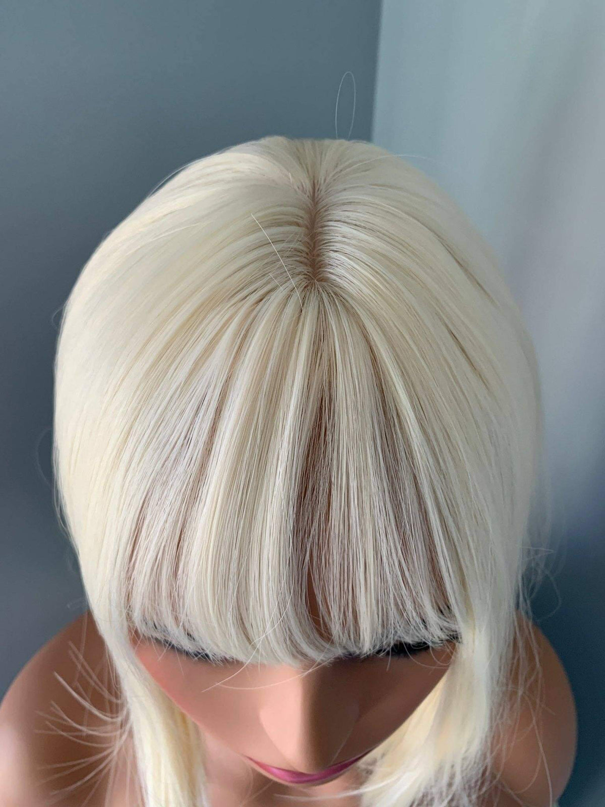 Blonde wig on a mannequin head against a plain background