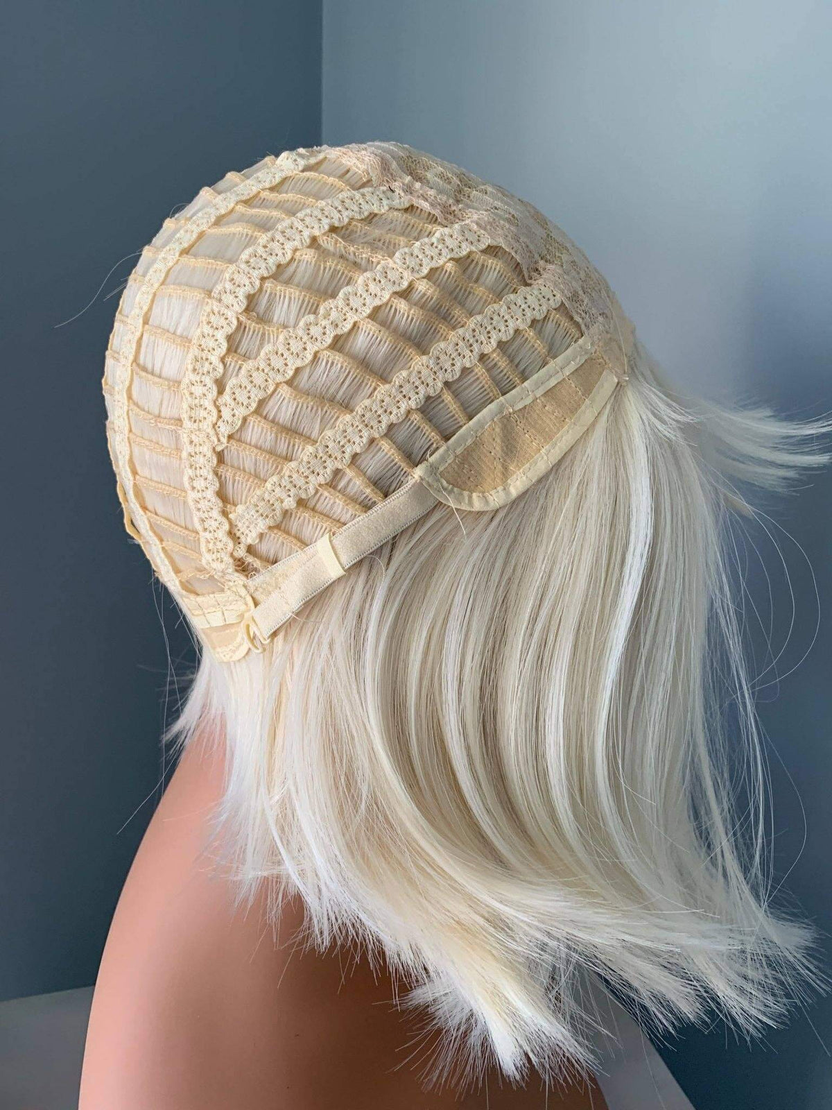 Beige lace headband worn by a person with blonde hair against a dark background