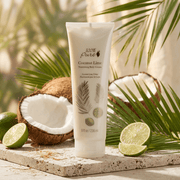 Tube of 100% Pure Coconut Lime Nourishing Body Cream with coconuts and limes on a natural background