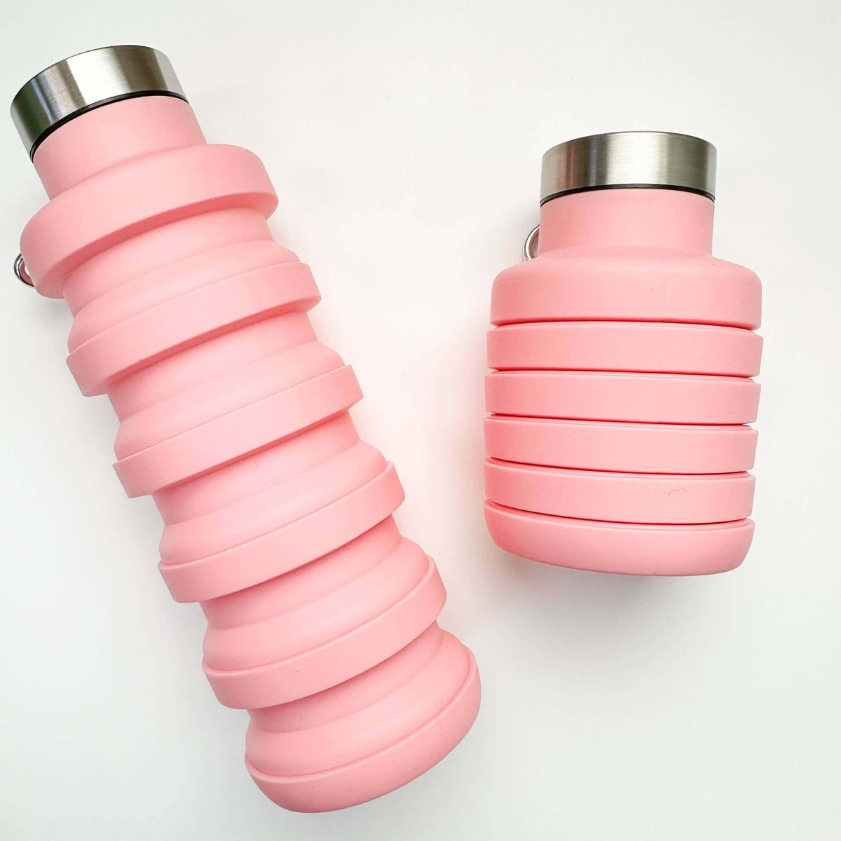 Two pink collapsible water bottles with silver caps on a white background