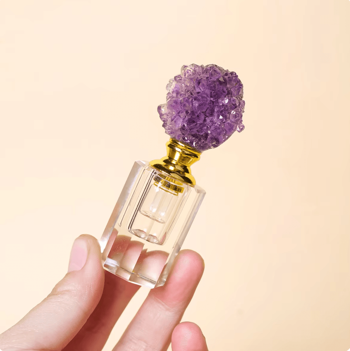 Crystal Gem Stone Essential Oil Bottle with amethyst gemstone topper held in hand against a light background.