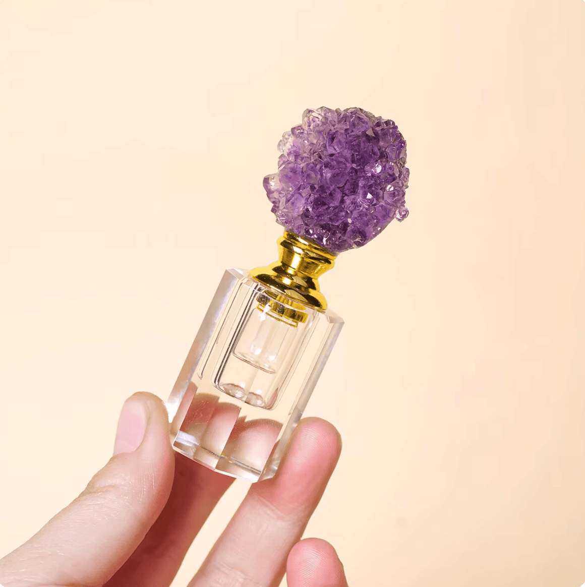 Crystal Gem Stone Essential Oil Bottle with amethyst gemstone topper held in hand against a light background.