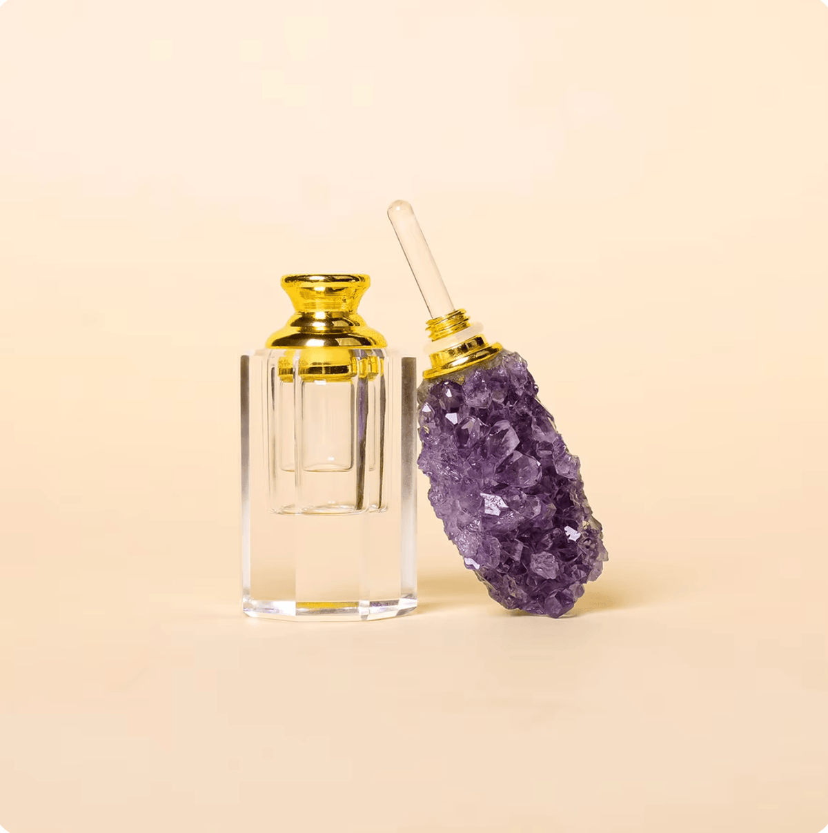 Crystal Gem Stone Essential Oil Bottle with purple gemstone and gold accents on a light background.