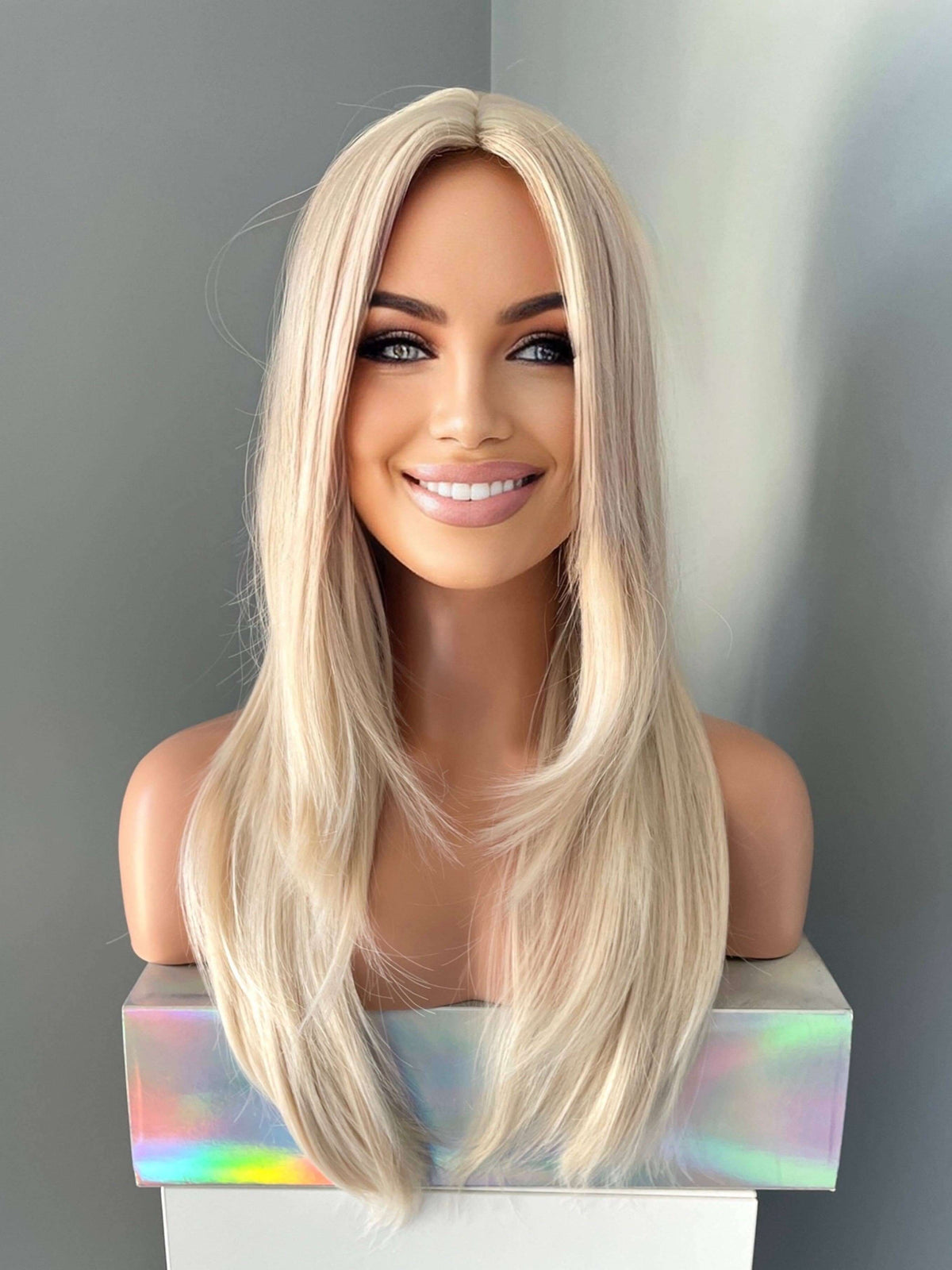Blonde wig on a mannequin head against a gray background