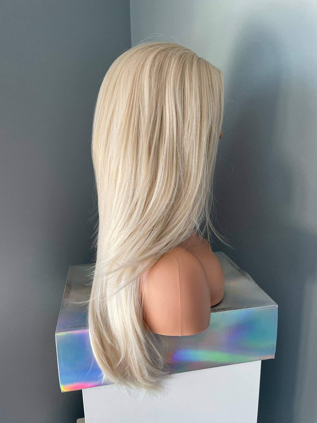 Blonde wig on a mannequin head against a plain background