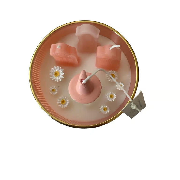 Pink teapot-shaped candle with flowers on a white background