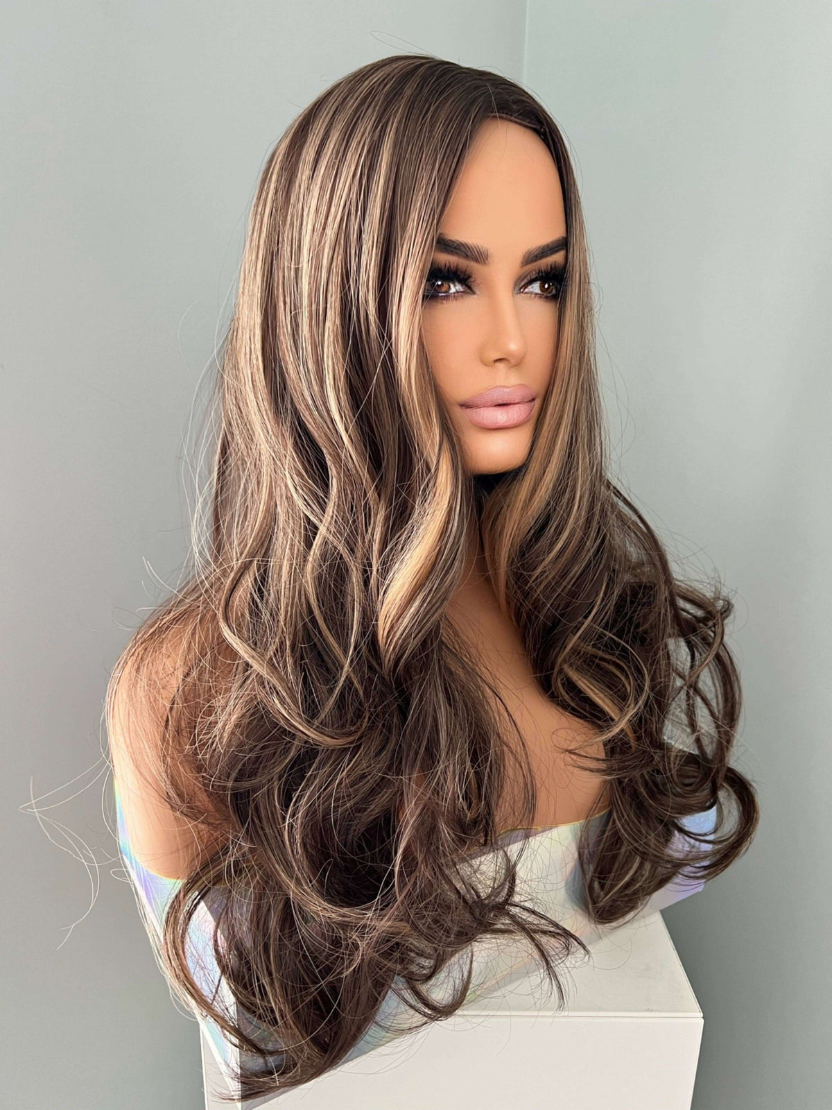 Long brown curled wig with highlights featuring cascading curls and a layered style for added volume.