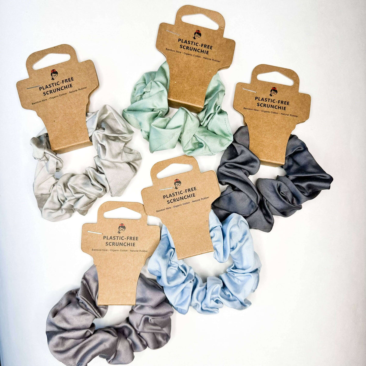 Set of plastic-free scrunchies in various colors with cardboard packaging on a white background